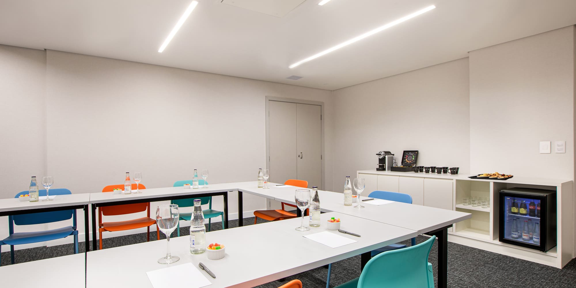 a room with white tables and colorful chairs