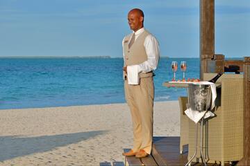 a man standing on a deck with a tray of wine and a tray of food