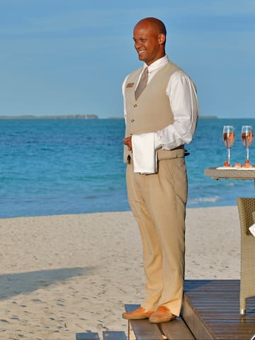 a man standing on a deck with a tray of wine and a tray of food