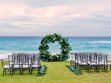 a wedding ceremony set up with chairs and a wreath
