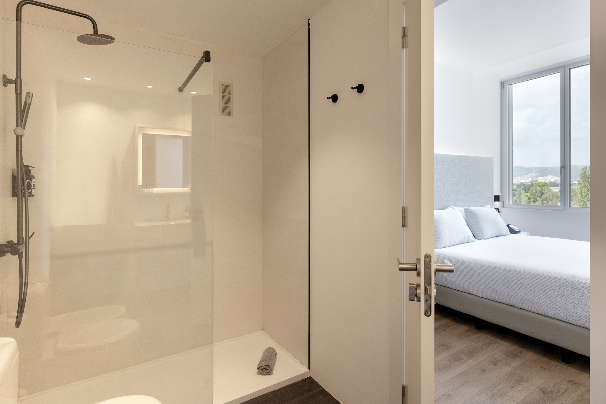 a bathroom with a glass shower and a bed