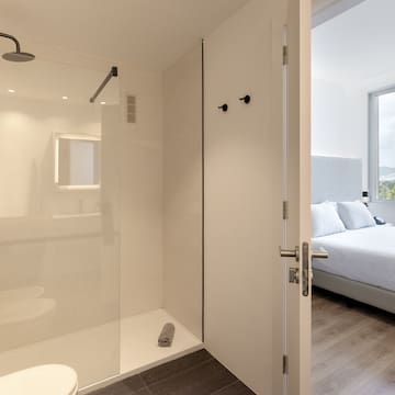 a bathroom with a glass shower and a bed