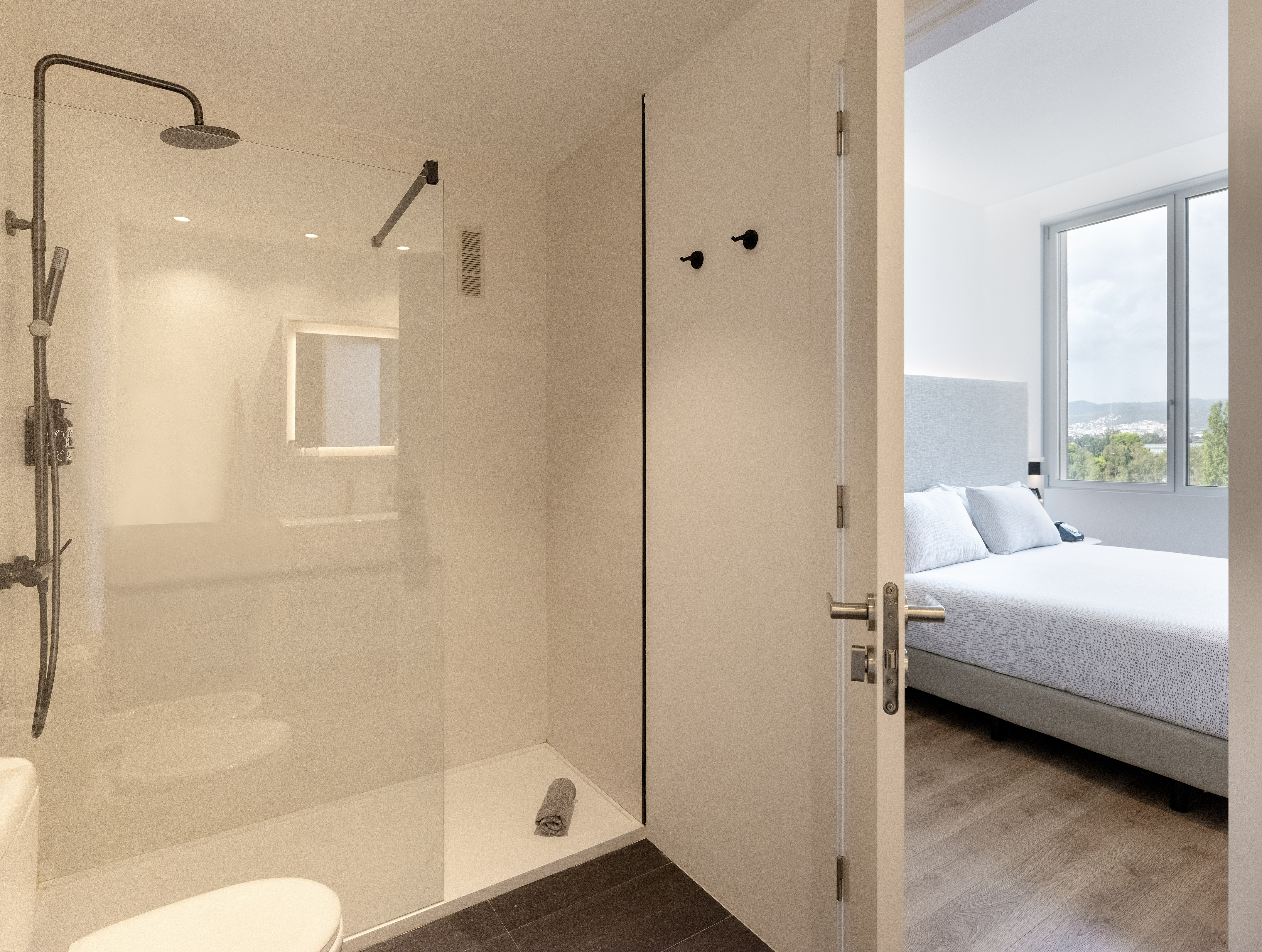 a bathroom with a glass shower and a bed