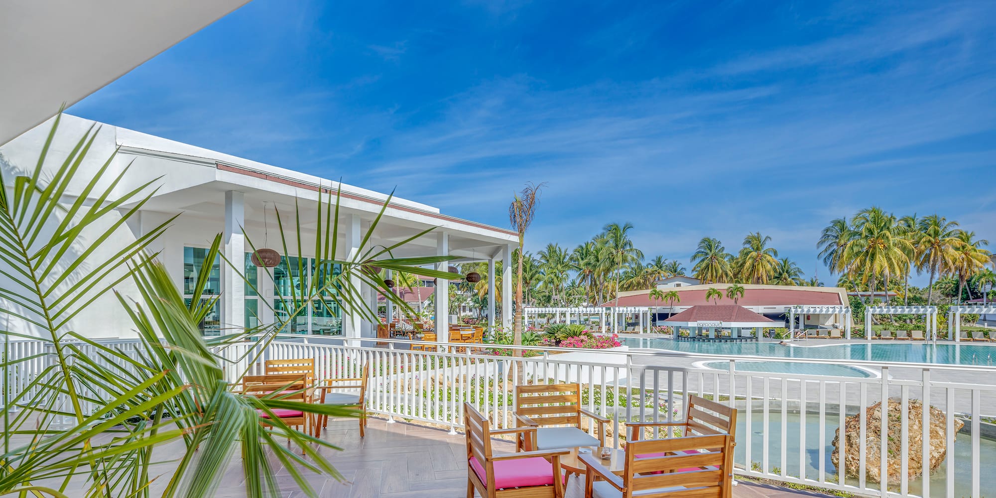 a patio with chairs and a pool in the background