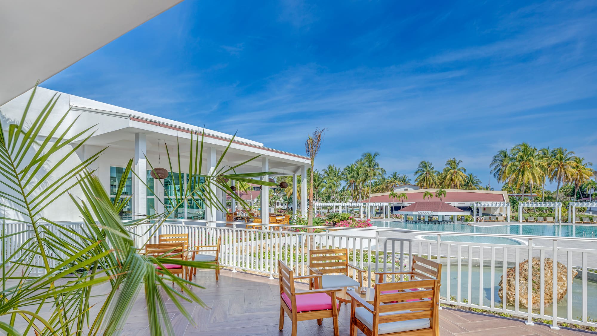 a patio with chairs and a pool in the background