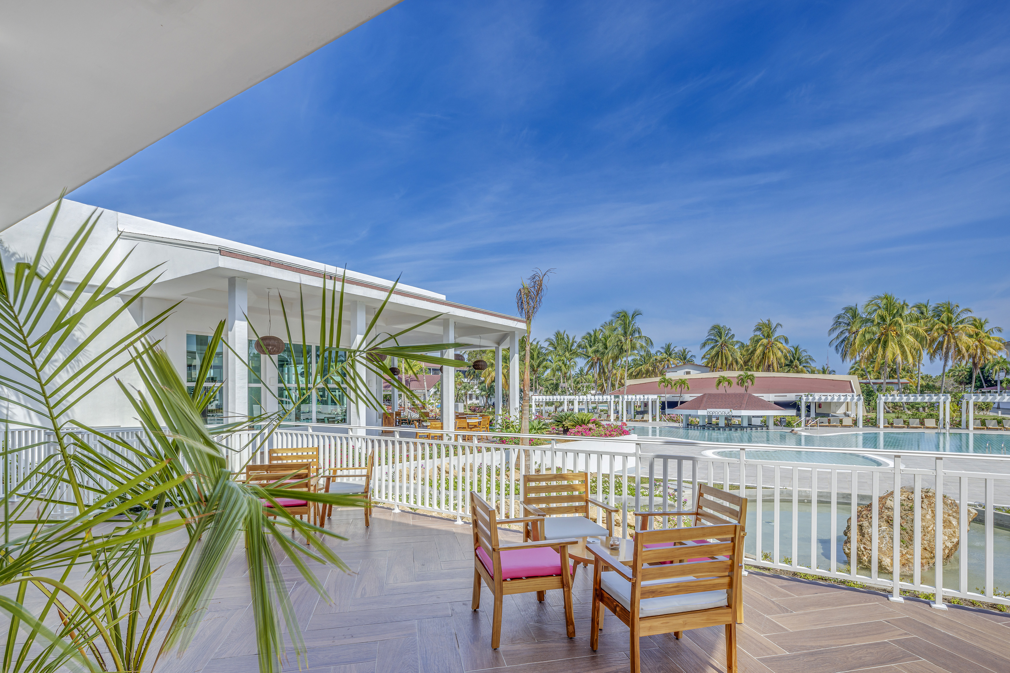 a patio with chairs and a pool in the background