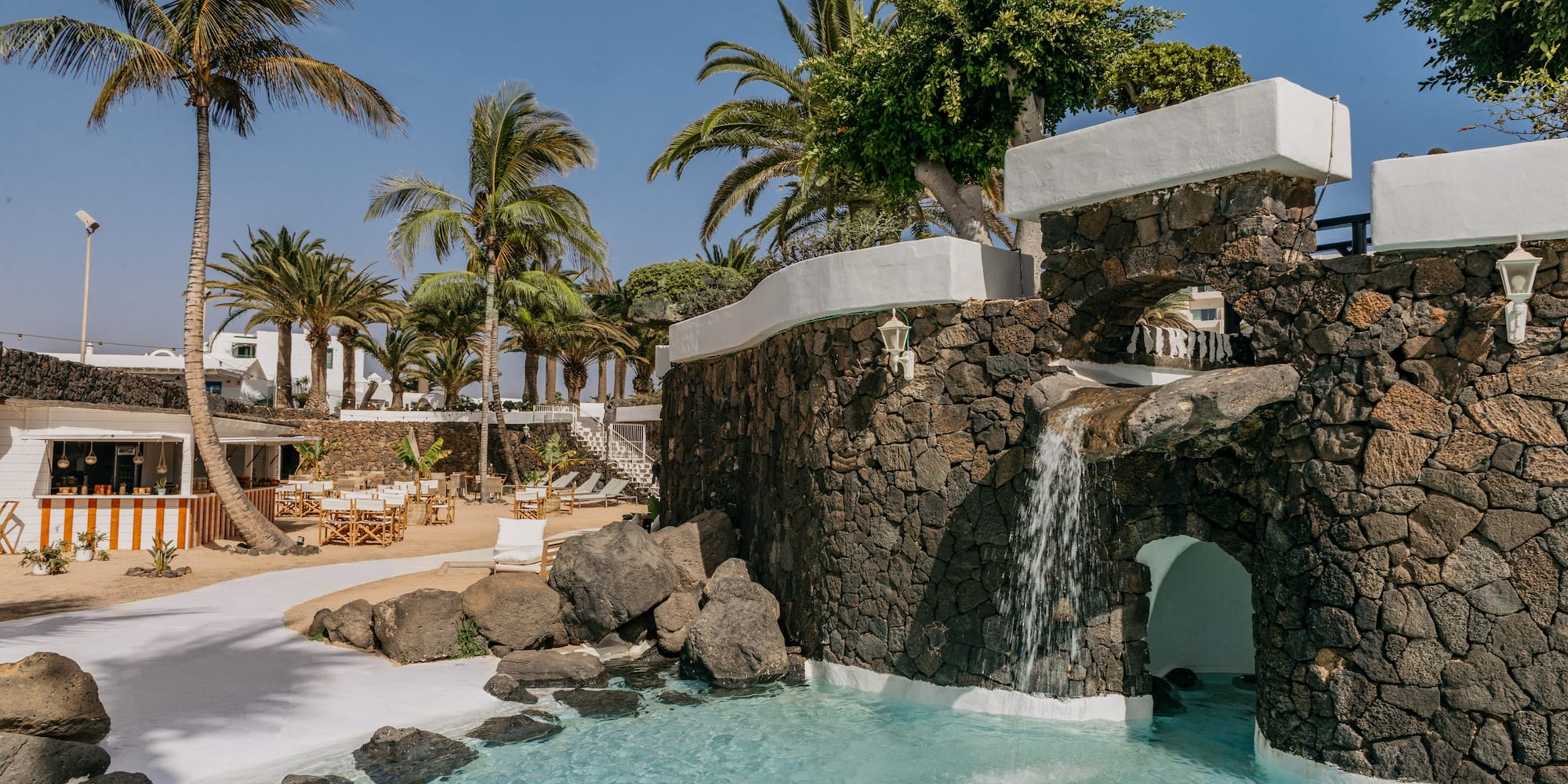 a pool with a waterfall and palm trees