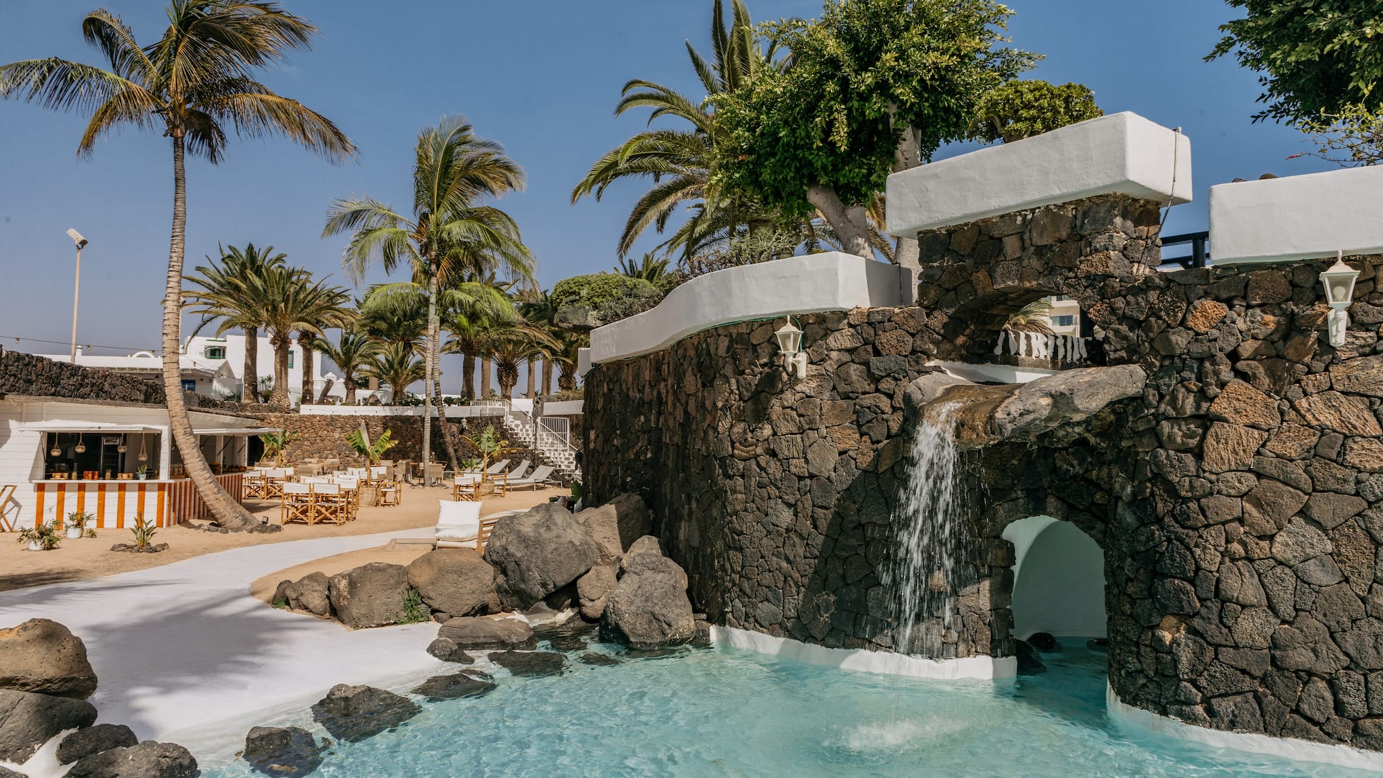 a pool with a waterfall and palm trees