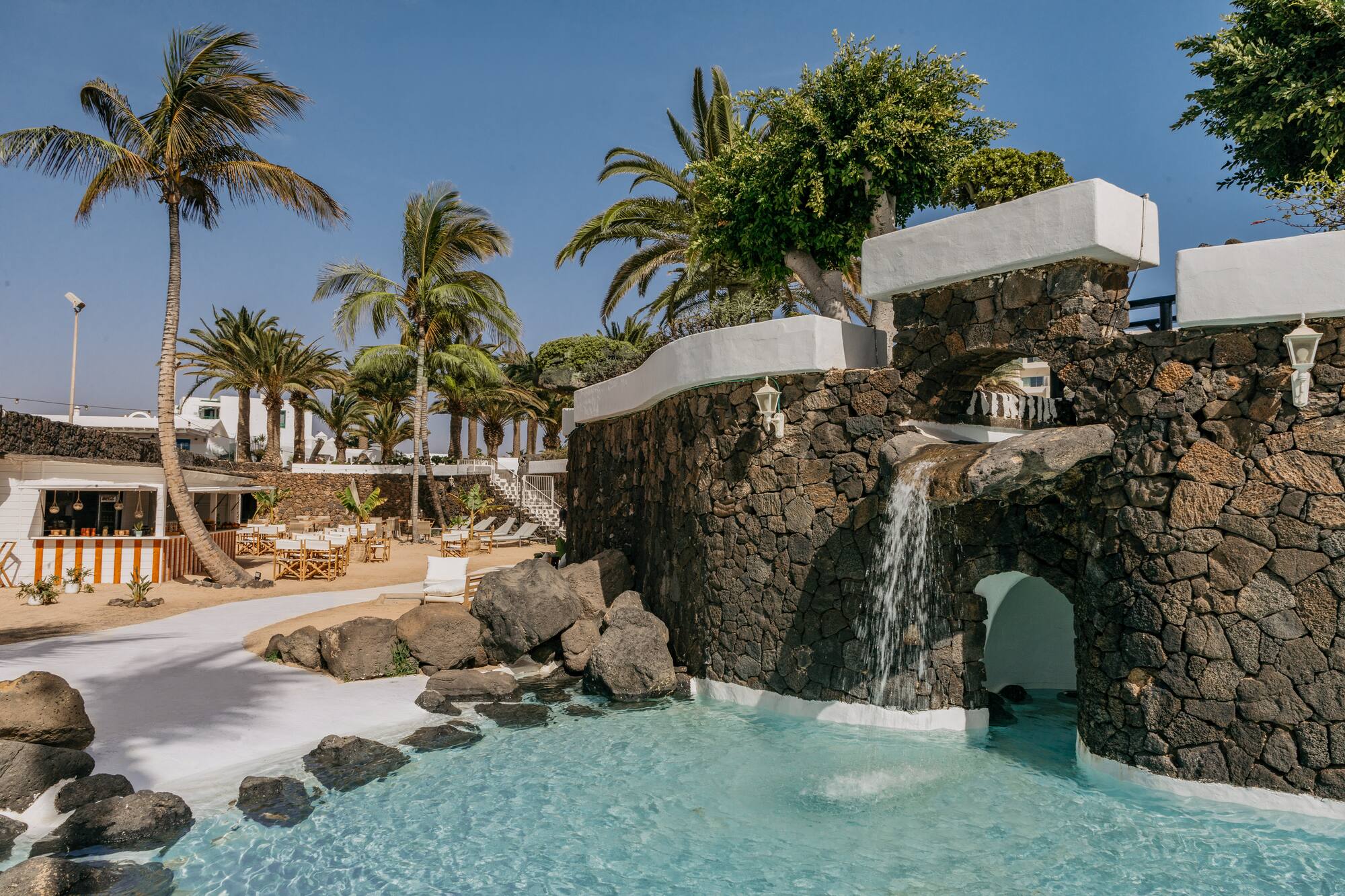 a pool with a waterfall and palm trees