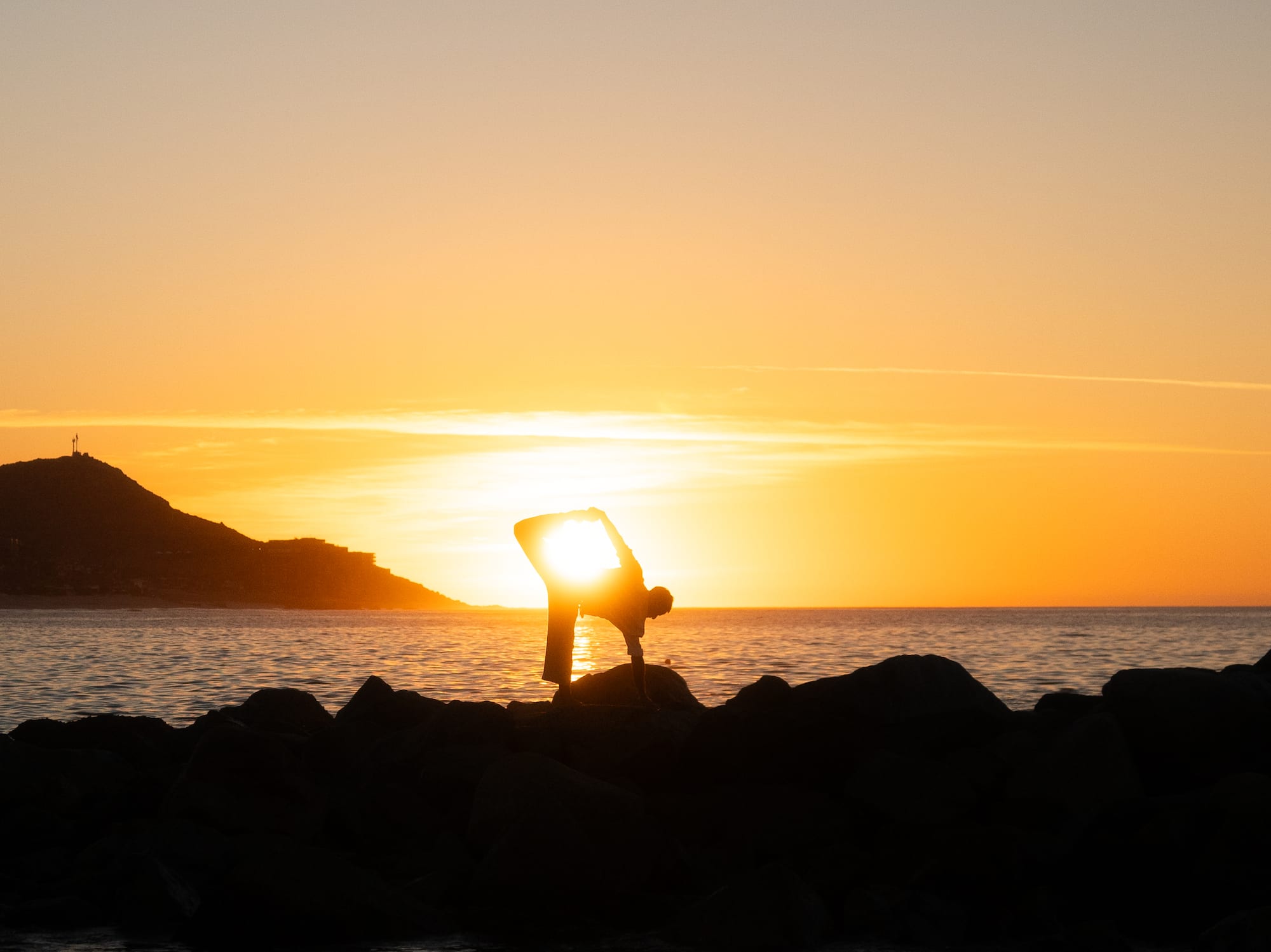 a person doing yoga on a rock by the water