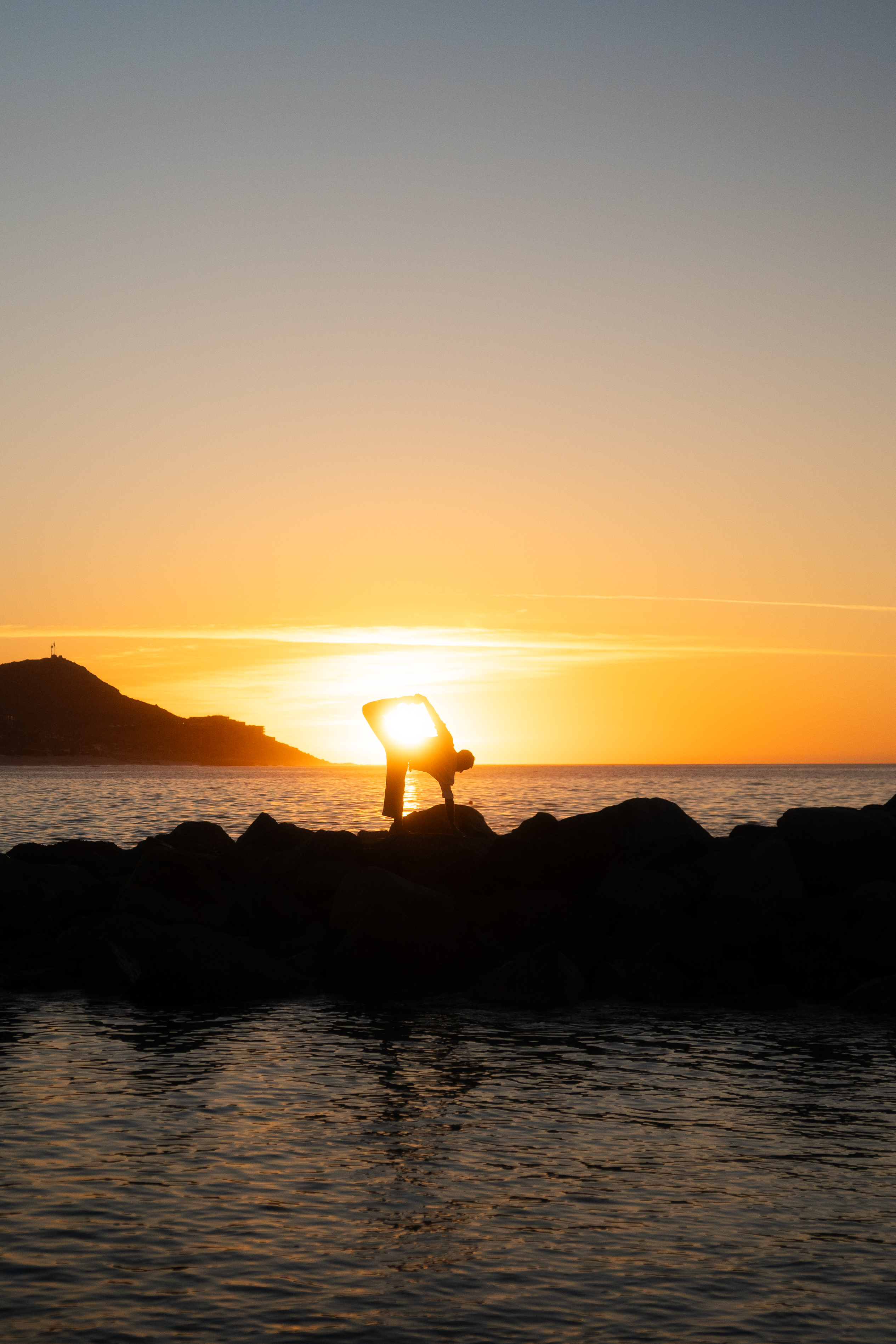 a person doing yoga on a rock by the water