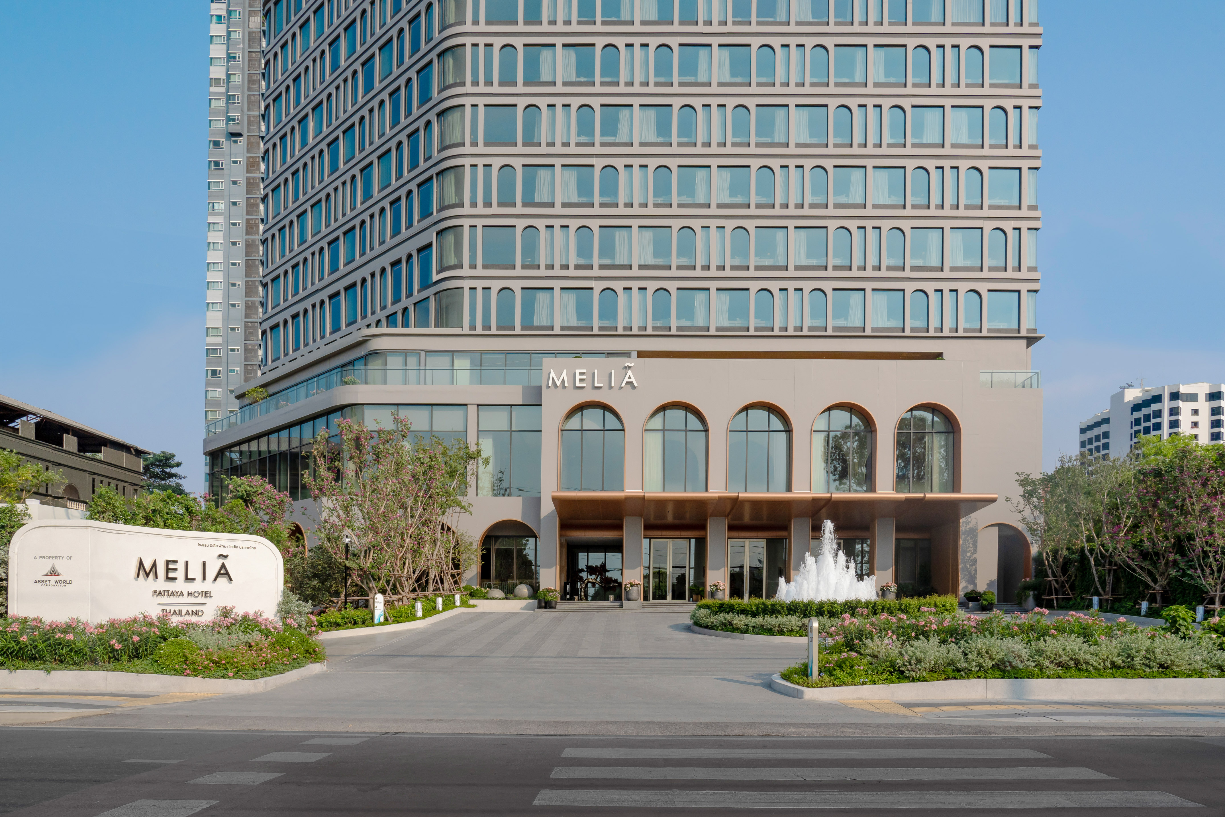 Modern Melia Pattaya Hotel facade with arched windows, entrance, and fountain.