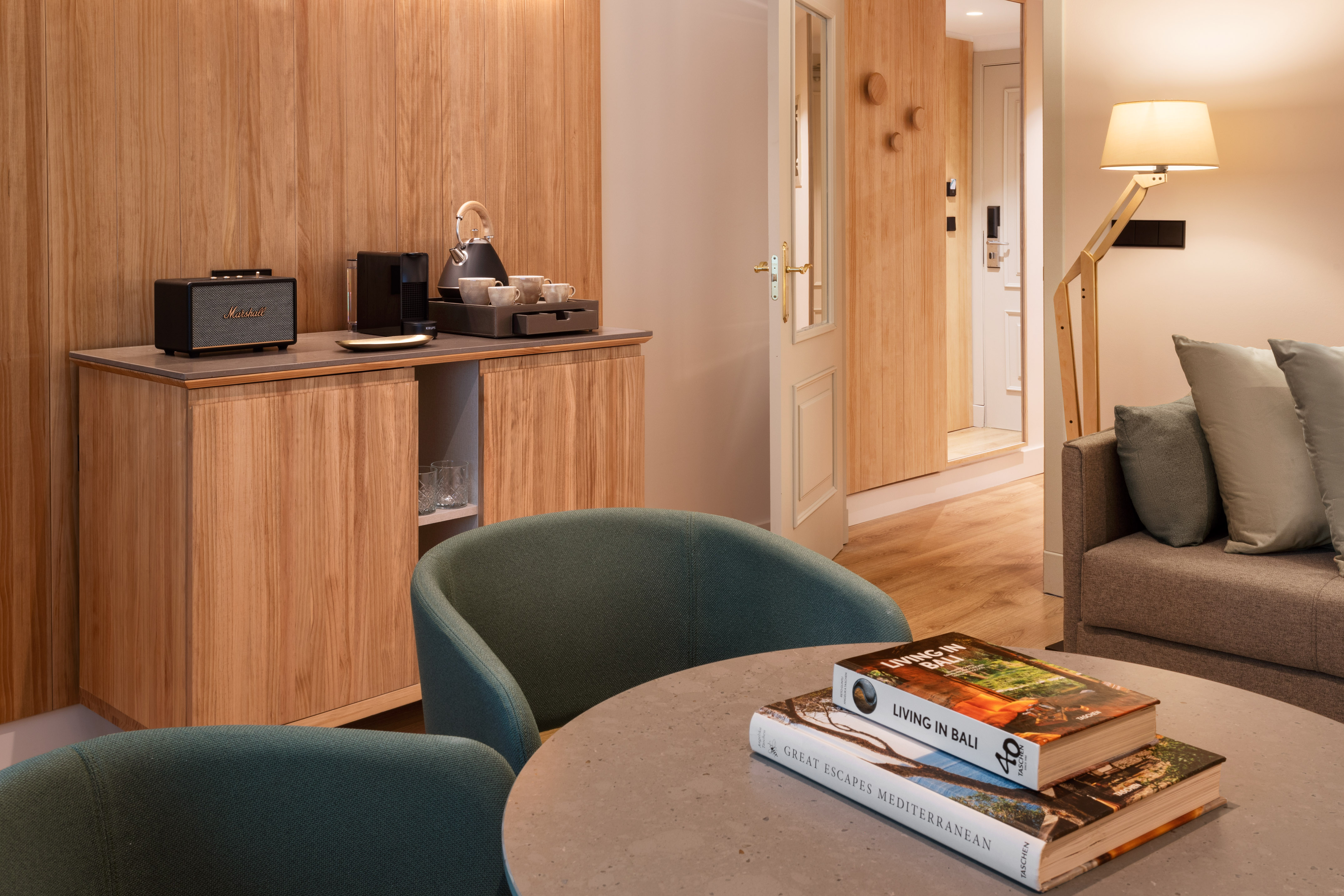 Hotel living area: wooden cabinet, coffee machine, Marshall speaker, armchairs.
