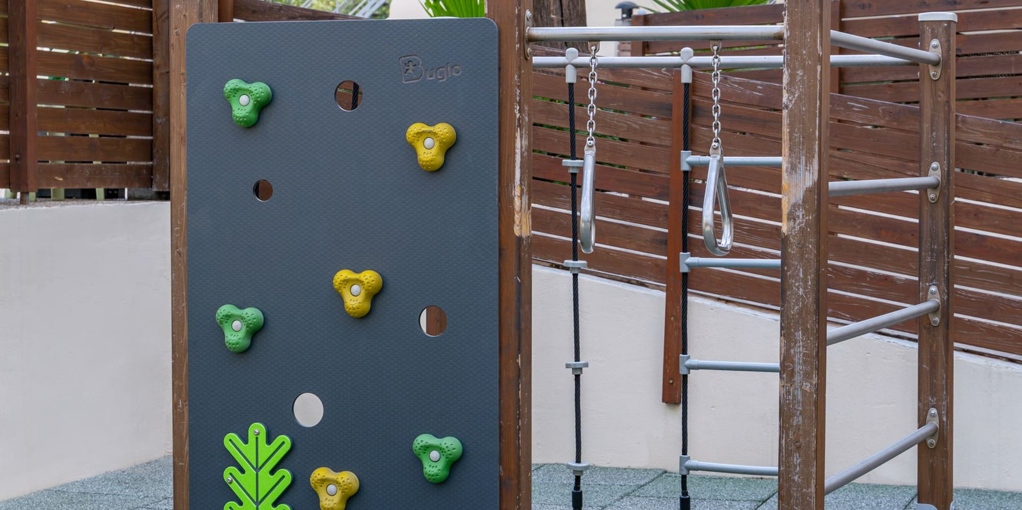 Outdoor playground with climbing wall, monkey bars, and safety flooring for kids.