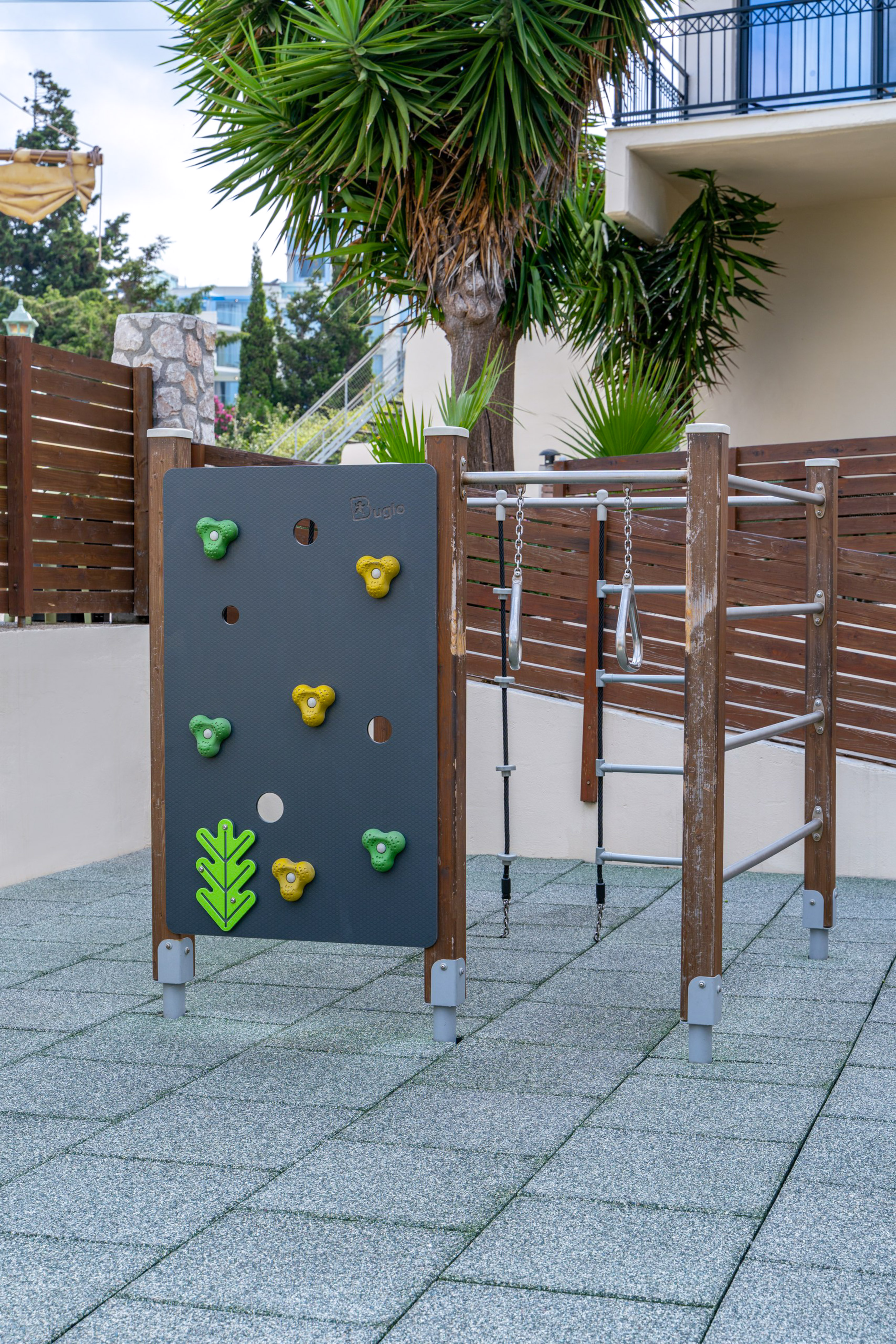 Outdoor playground with climbing wall, monkey bars, and safety flooring for kids.