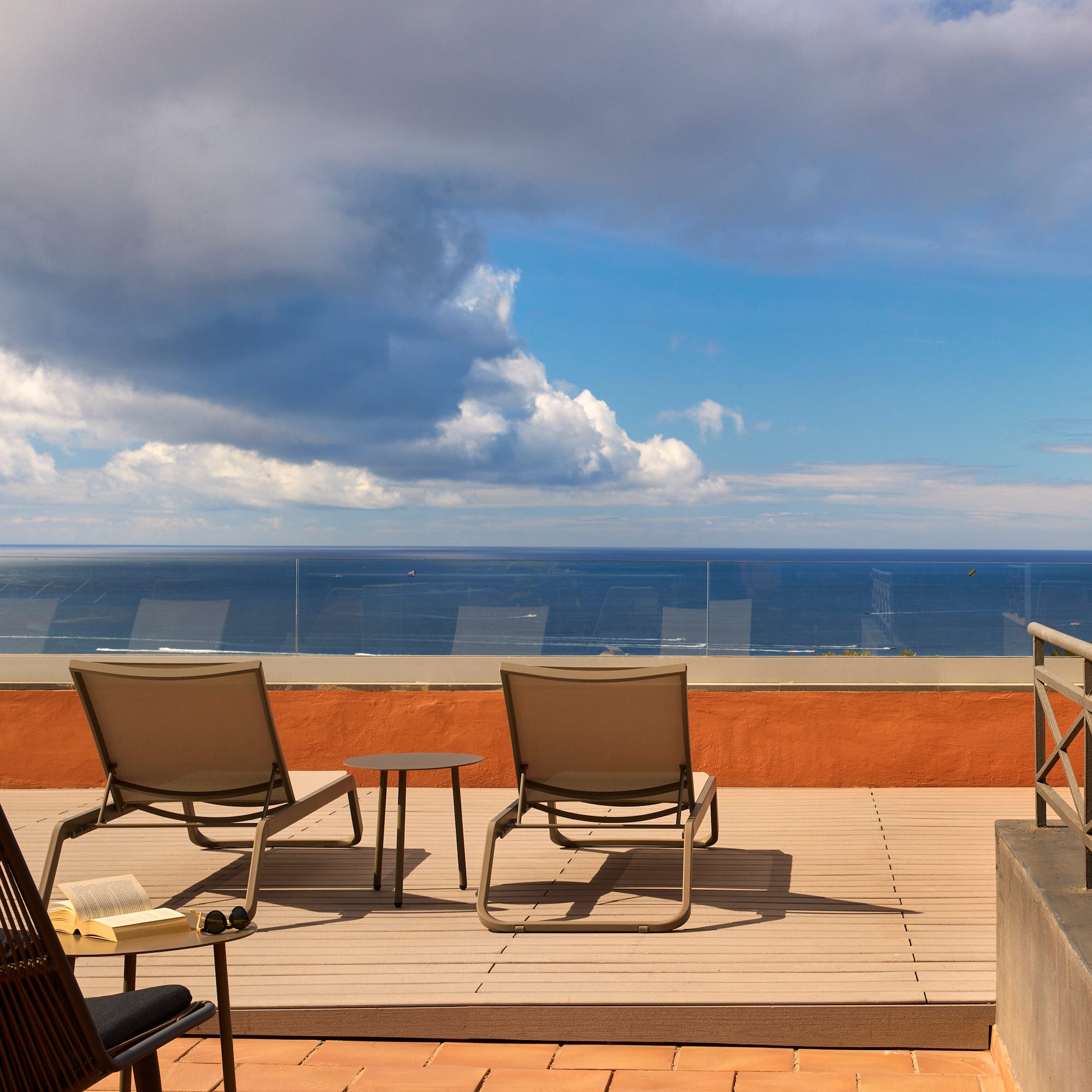 a deck with chairs and a table overlooking the ocean