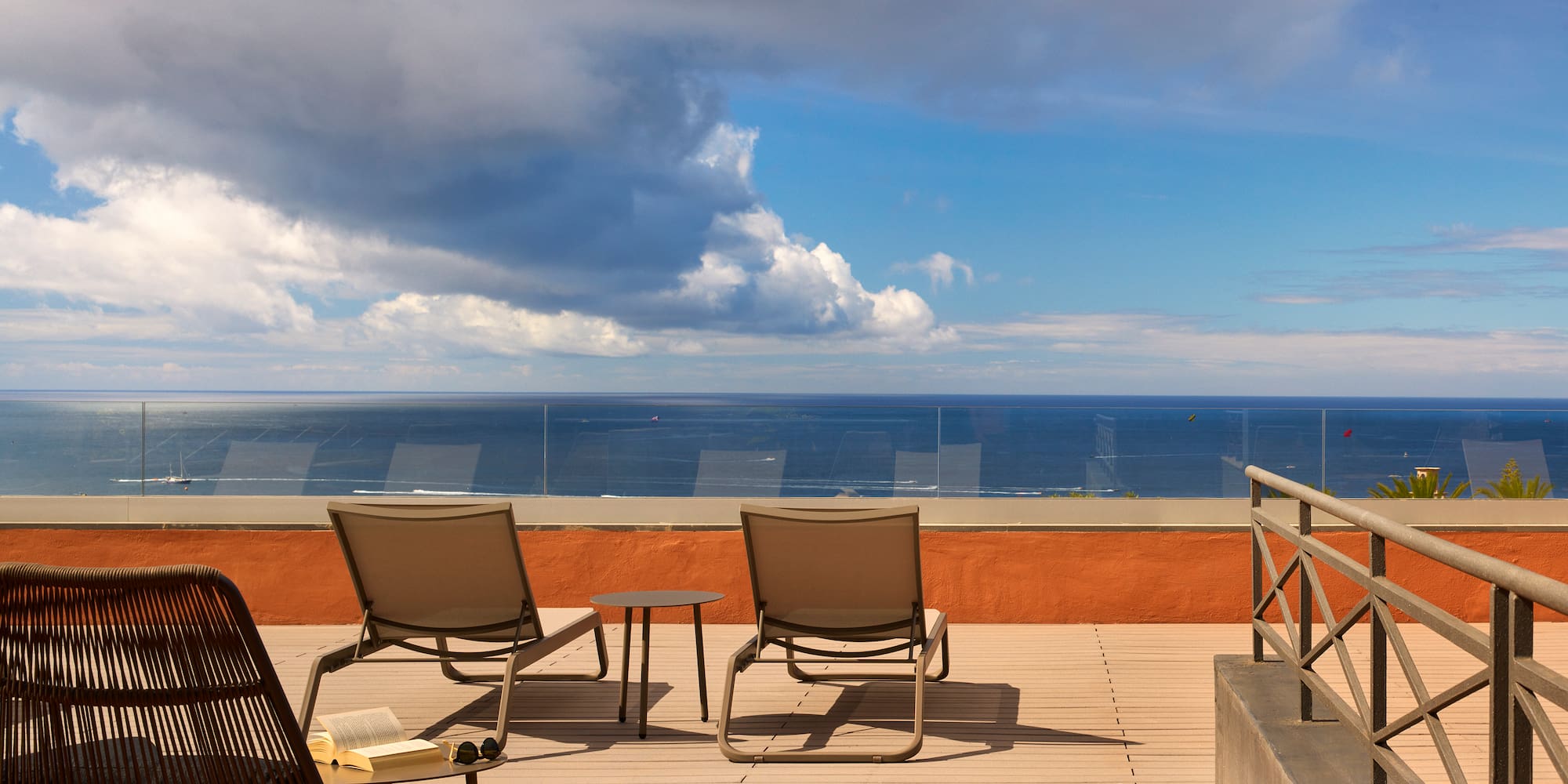 a deck with chairs and a table overlooking the ocean