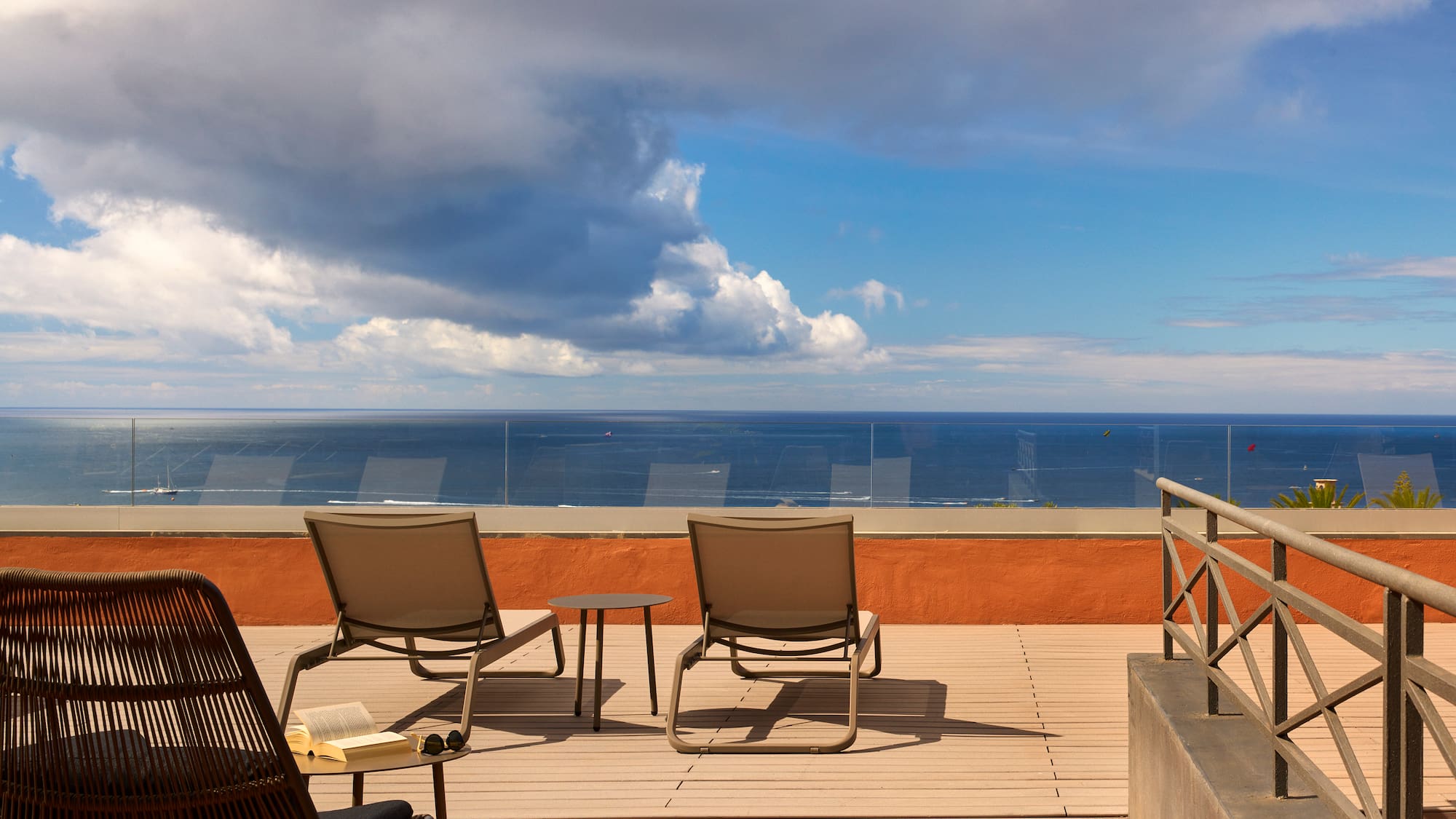 a deck with chairs and a table overlooking the ocean