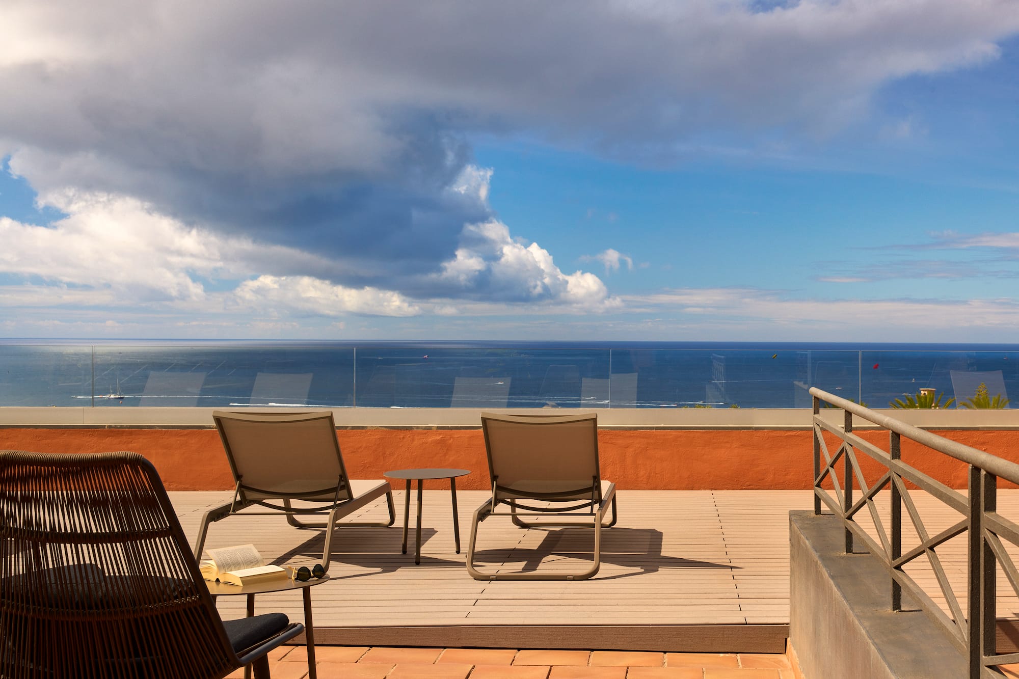 a deck with chairs and a table overlooking the ocean