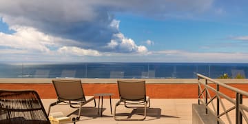 a deck with chairs and a table overlooking the ocean