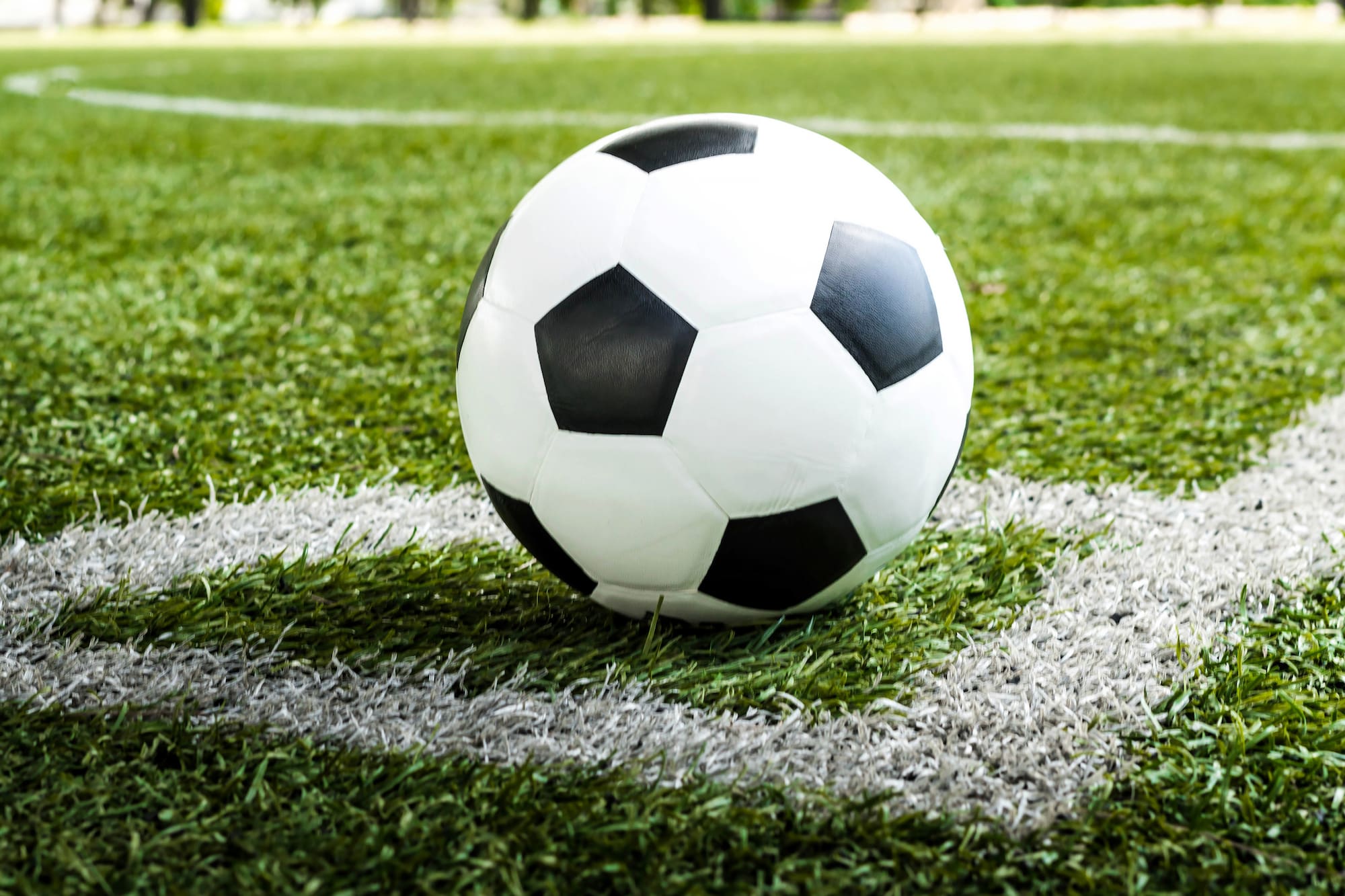Black and white soccer ball on a green football field, near the white line.