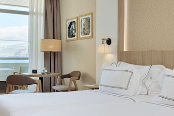 a bed with white sheets and a table in a hotel room