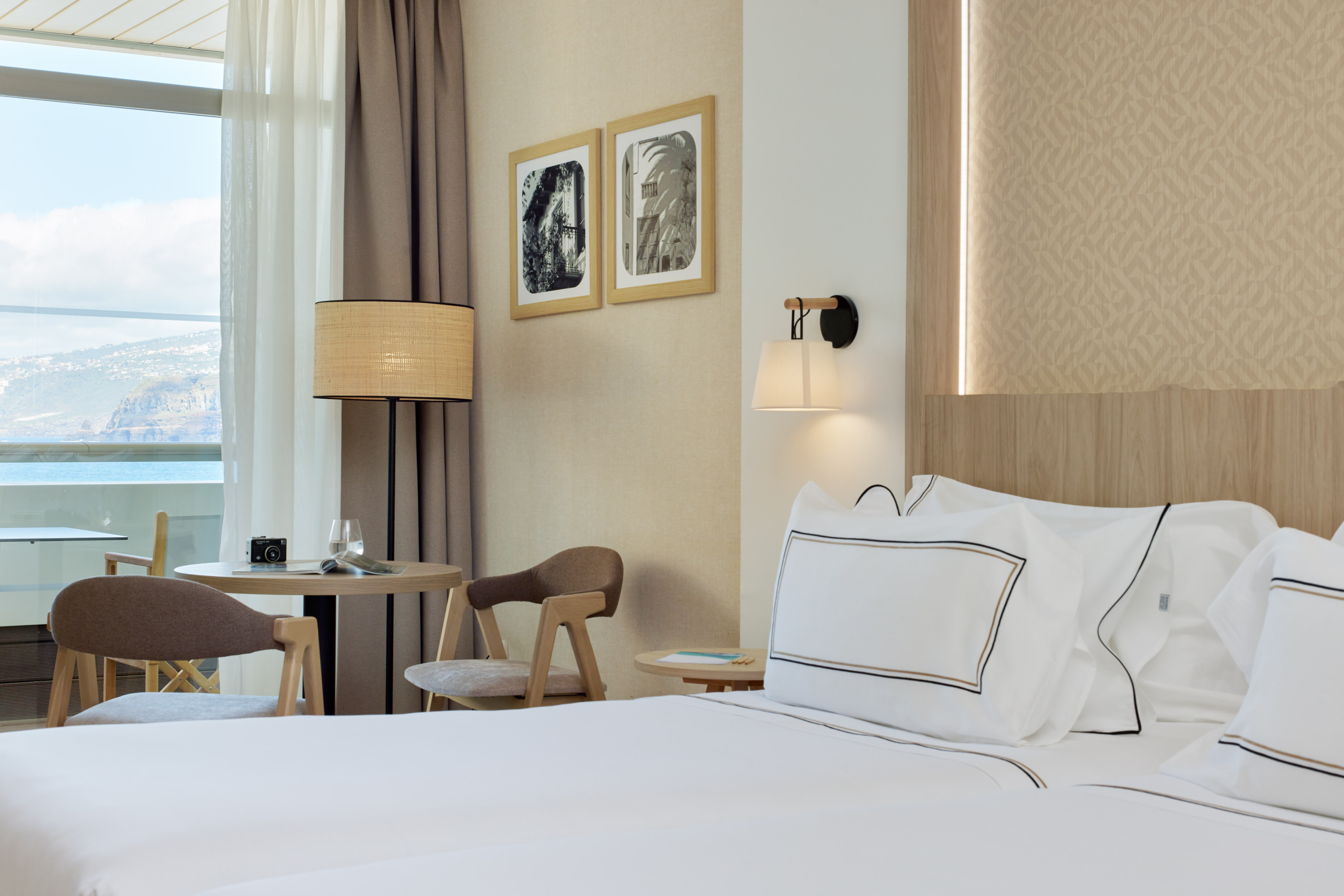 Hotel room with ocean view, large bed, sitting area, and modern decor.