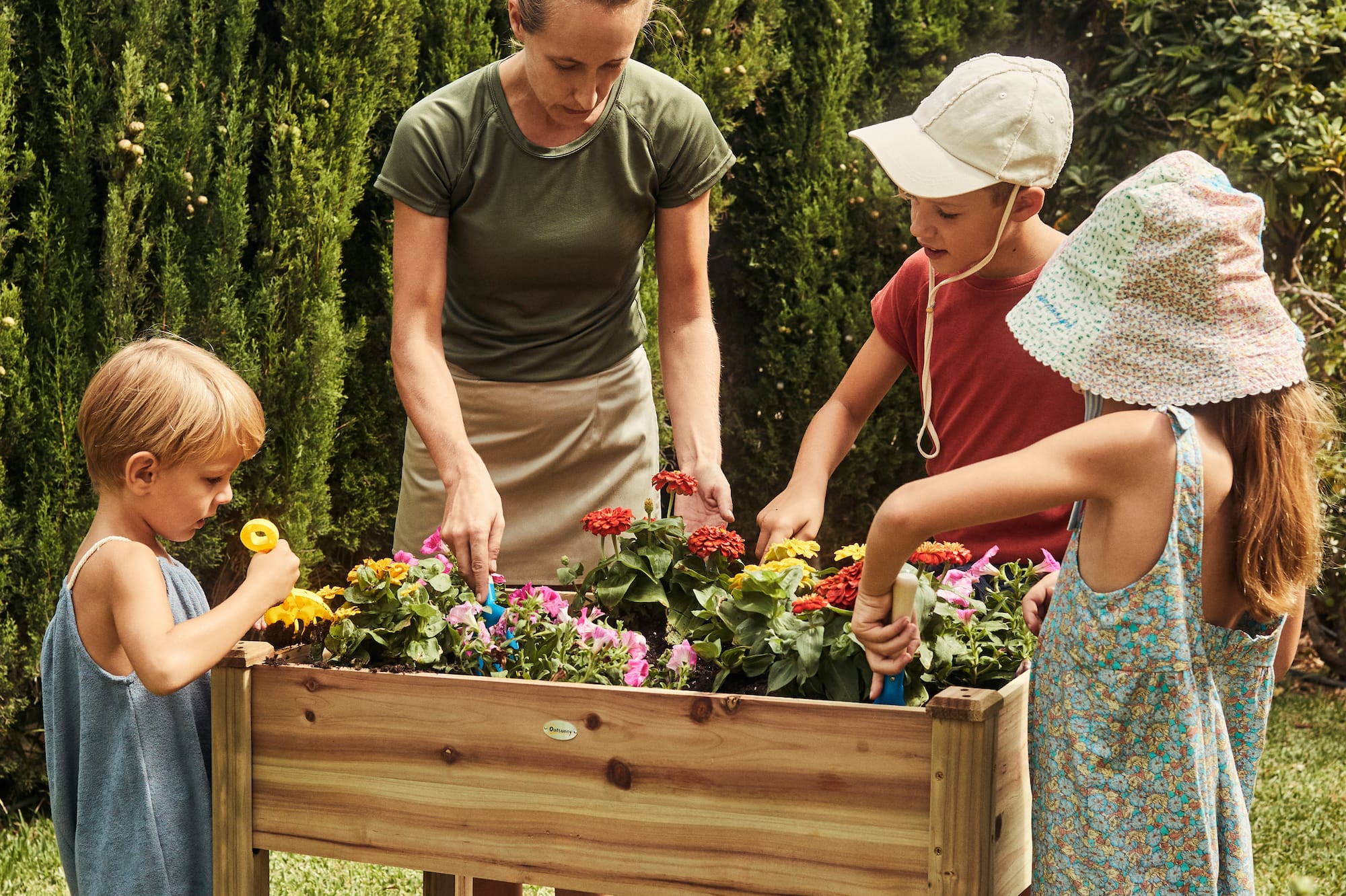 a woman and kids planting flowers in a garden