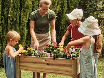 a woman and kids planting flowers in a garden