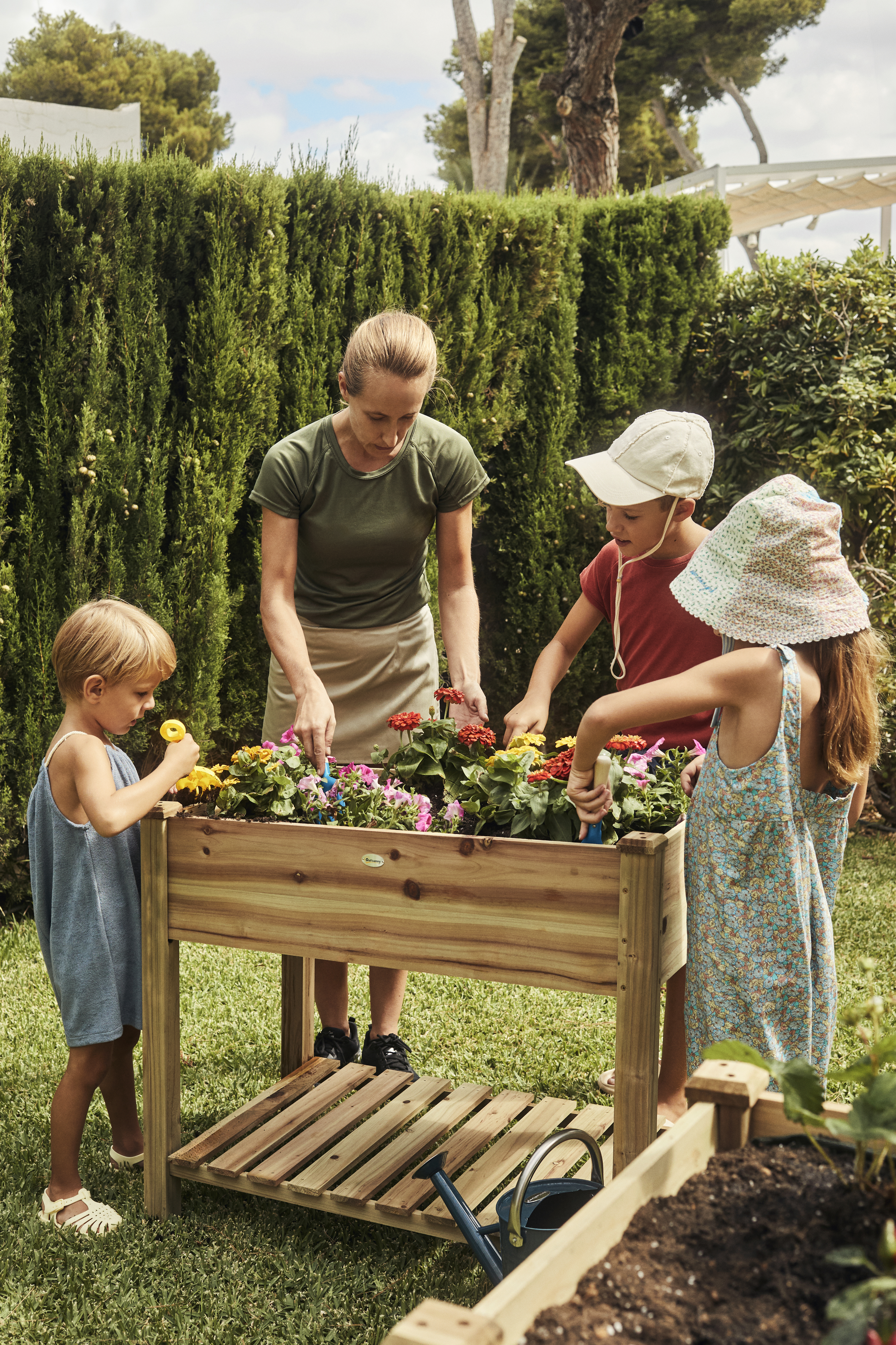 a woman and kids planting flowers in a garden
