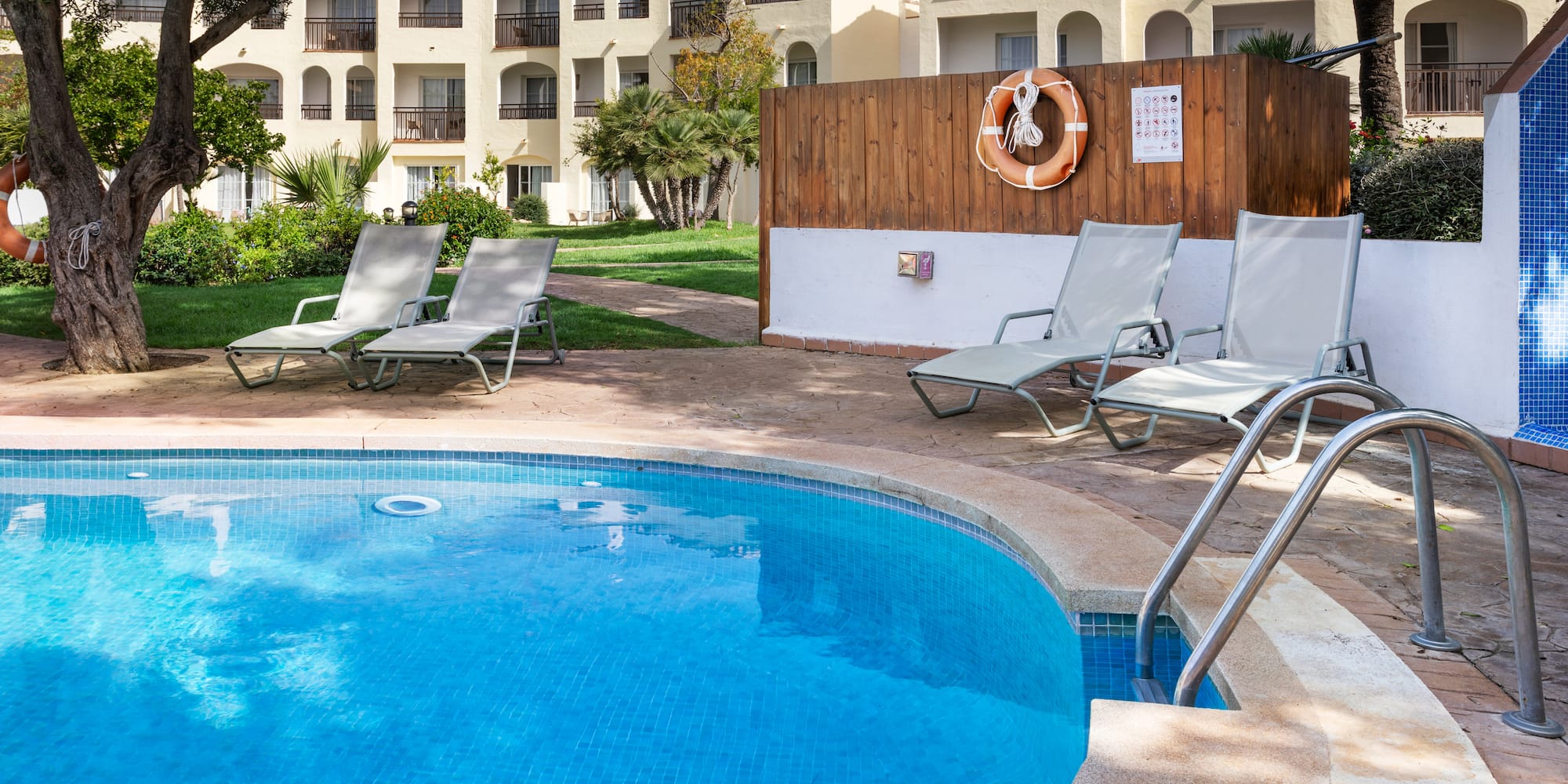 a pool with chairs and a fence in the background