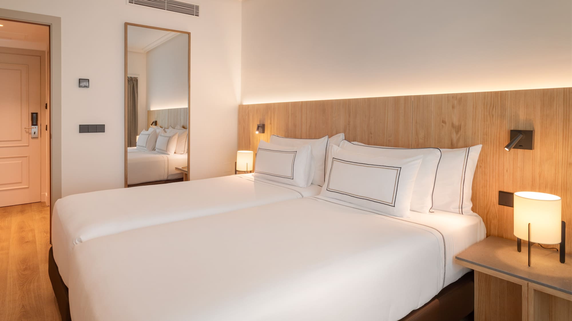 a bed with white sheets and a mirror