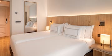 a bed with white sheets and a mirror