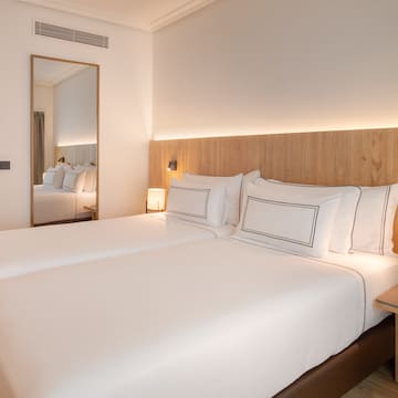 a bed with white sheets and a mirror