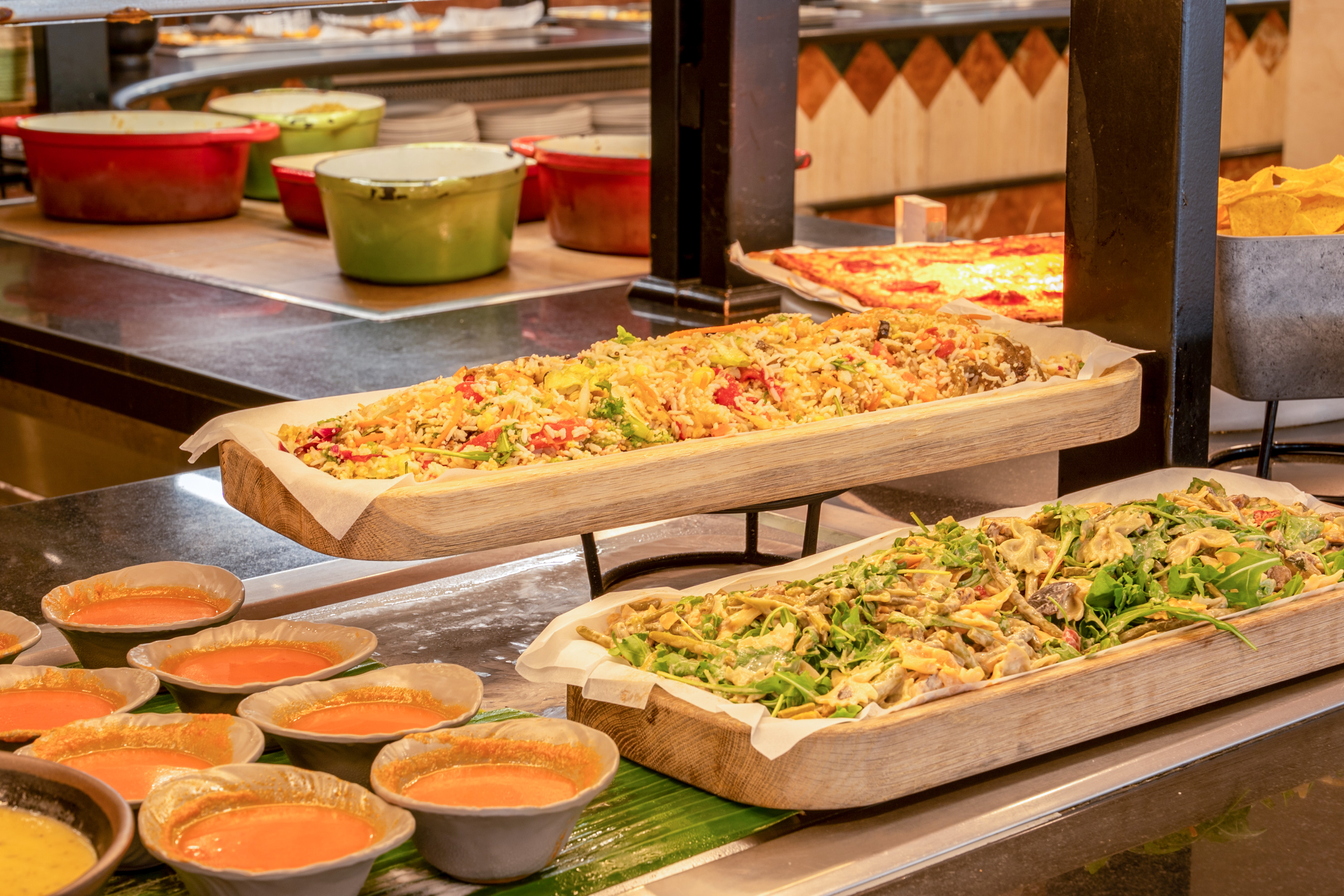 Varied buffet spread with rice salad, pasta salad, tomato soup, and pizza.