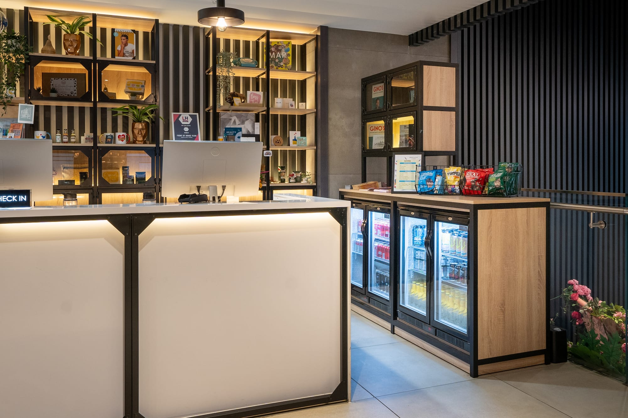 Modern hotel check-in desk with illuminated shelving and a snack kiosk.
