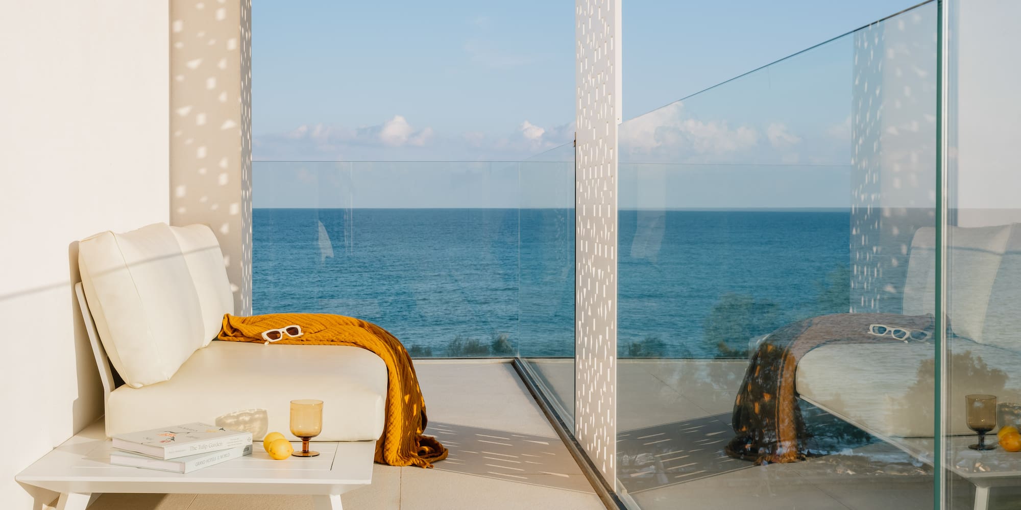 a white couch with a yellow blanket and a coffee table with a glass wall