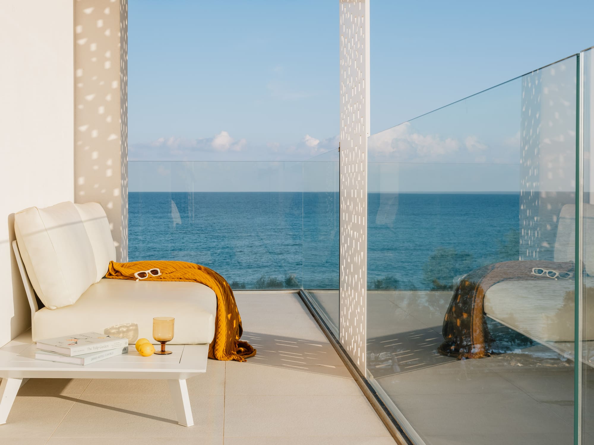 a white couch with a yellow blanket and a coffee table with a glass wall