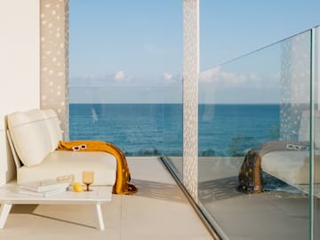 a white couch with a yellow blanket and a coffee table with a glass wall