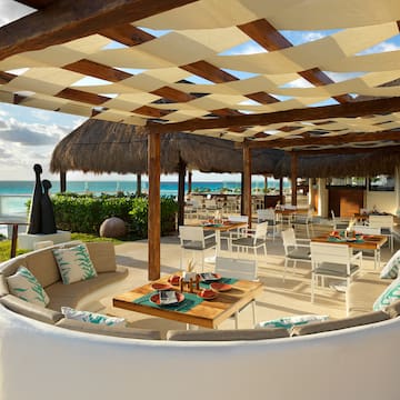 a patio with a large table and chairs and a beach