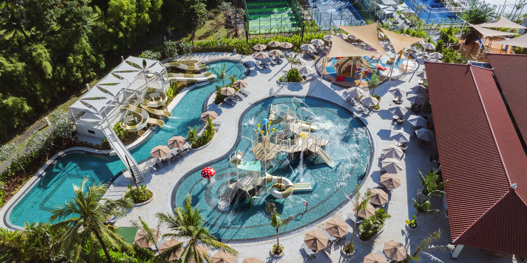 Aerial tropical resort water park: pools, thrilling water slides, lush landscaping.