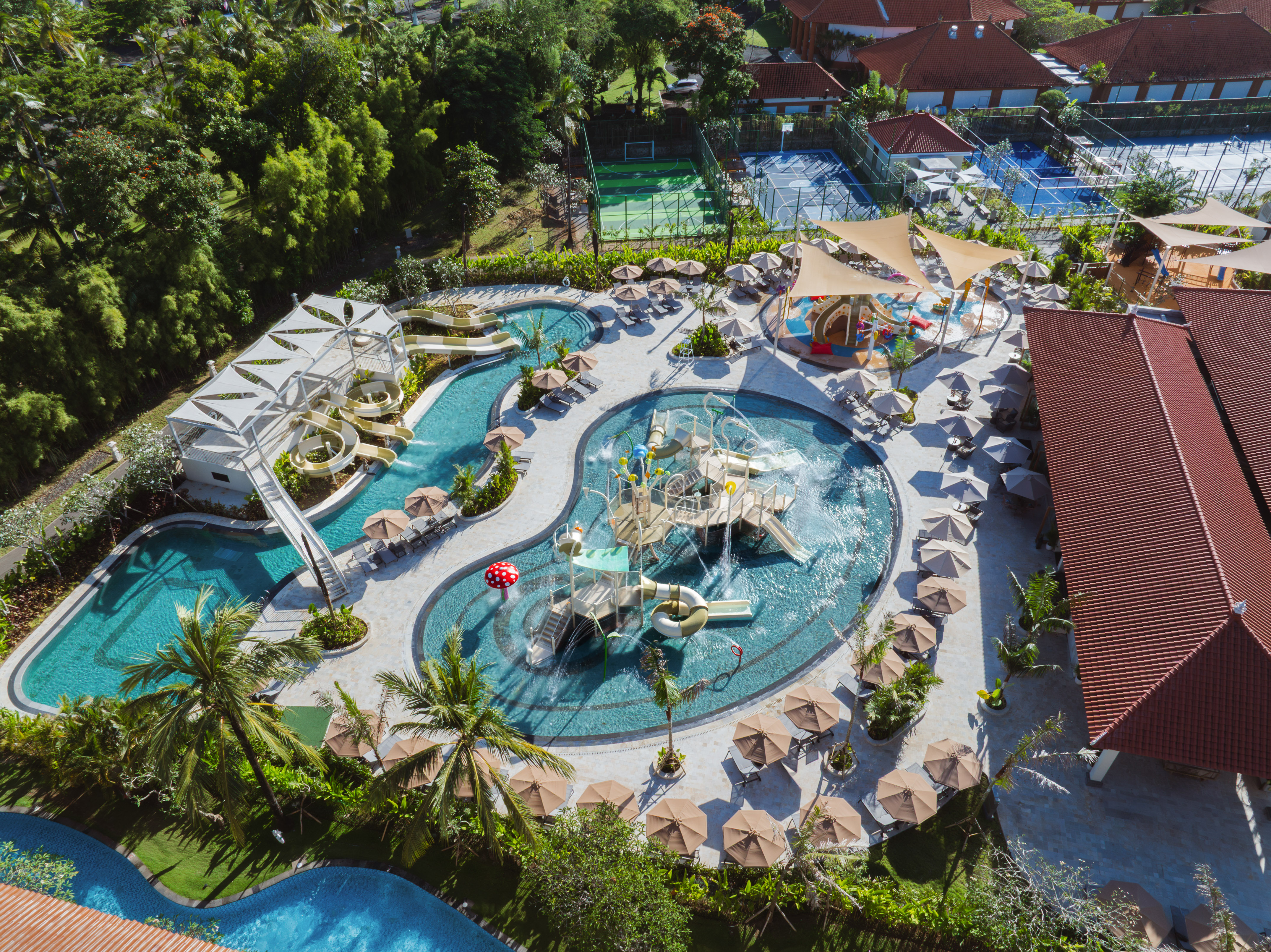 Aerial tropical resort water park: pools, thrilling water slides, lush landscaping.