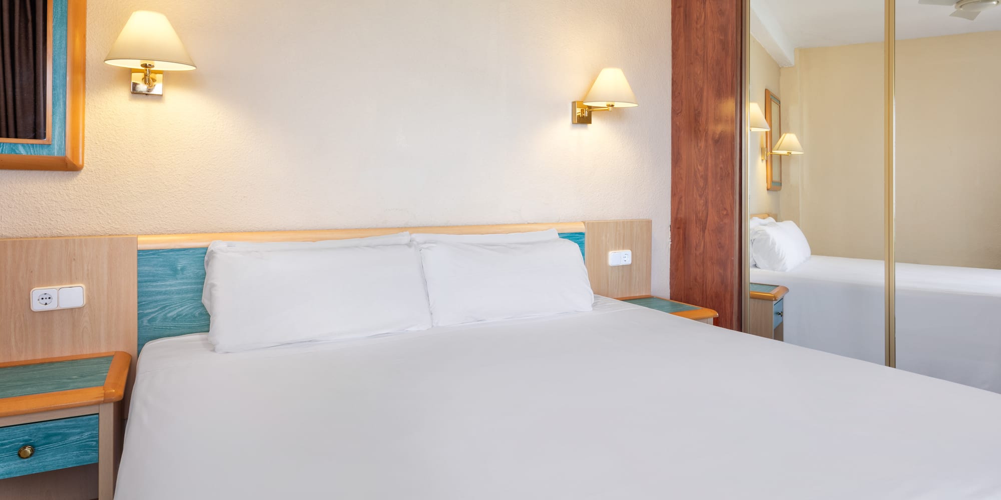 a bed with white sheets and a mirror