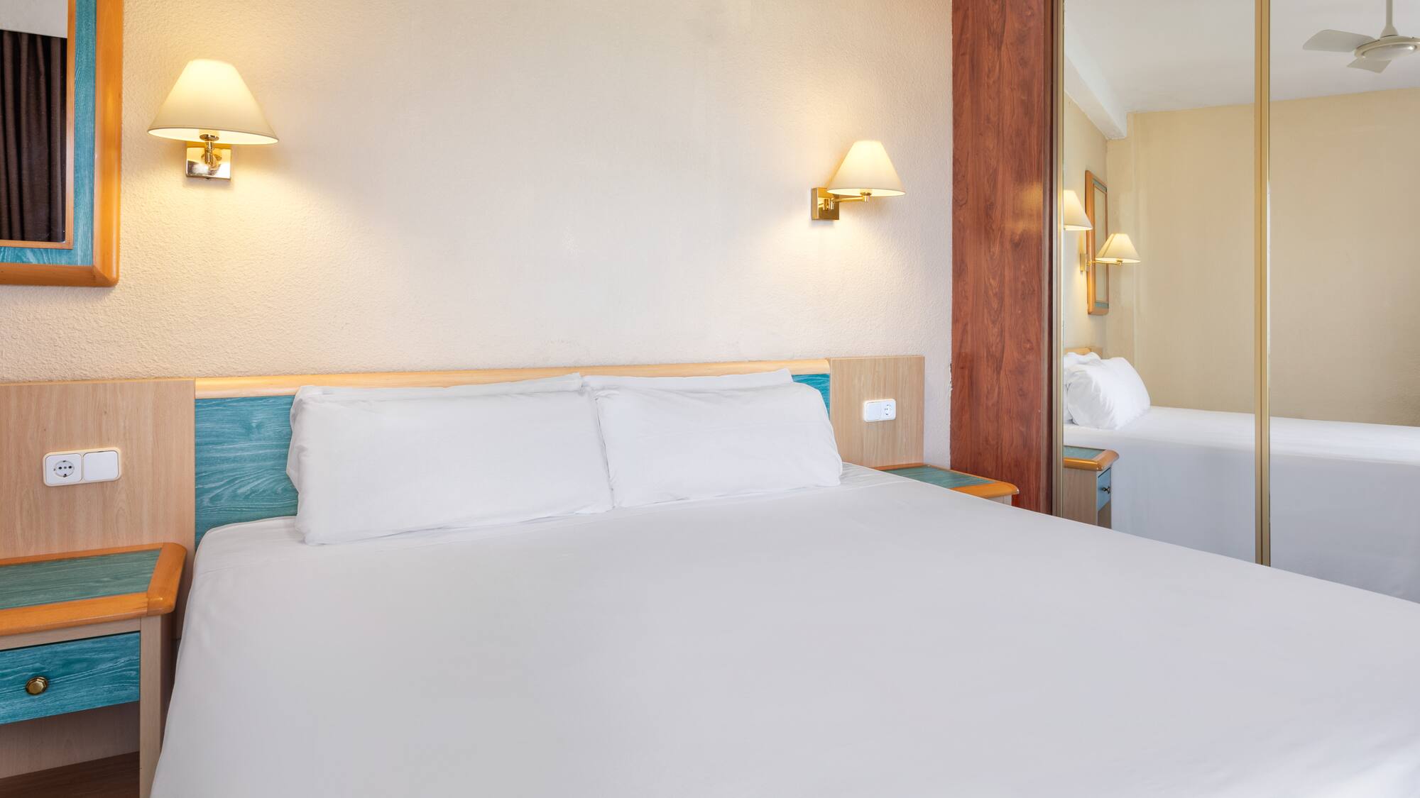 a bed with white sheets and a mirror