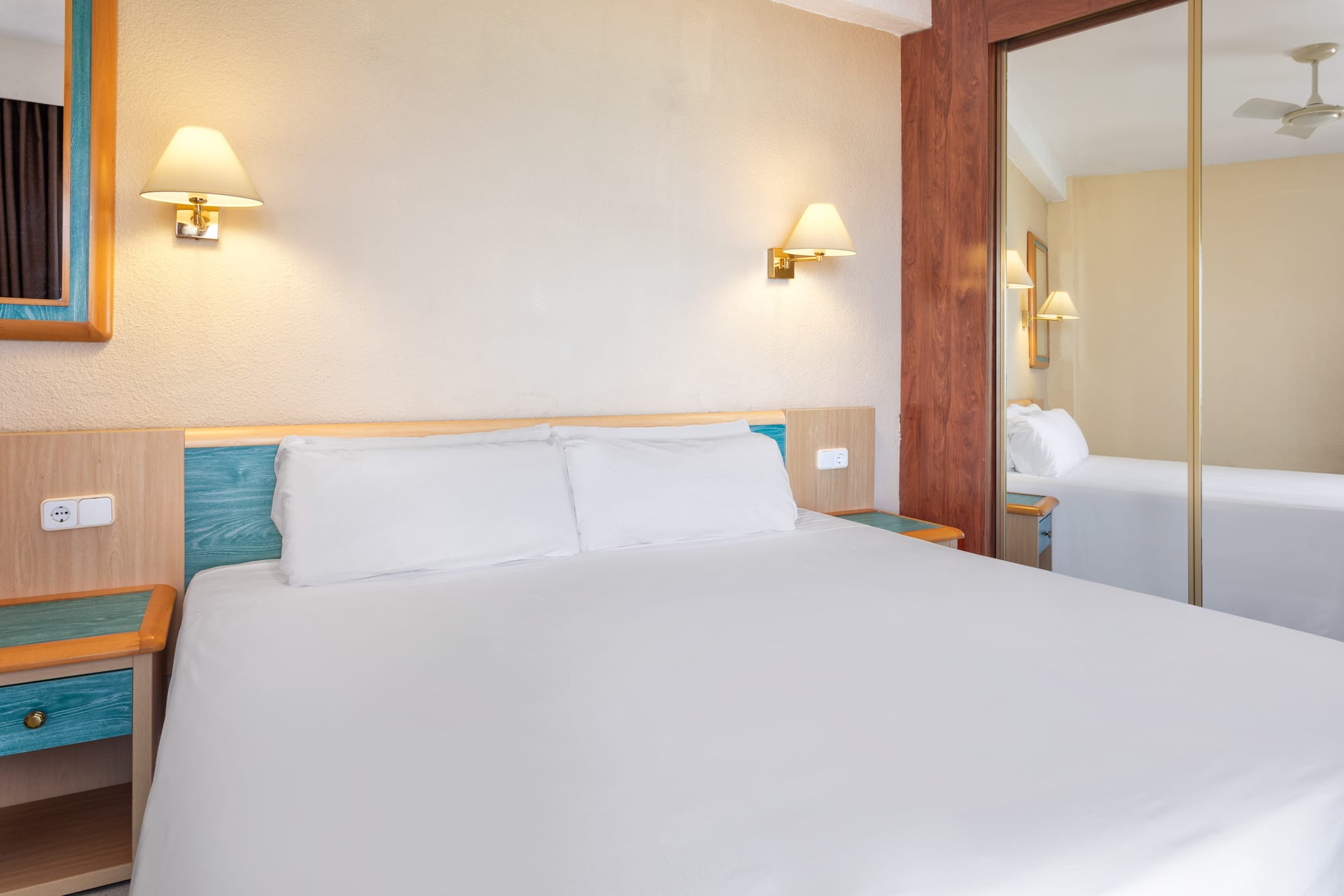 a bed with white sheets and a mirror