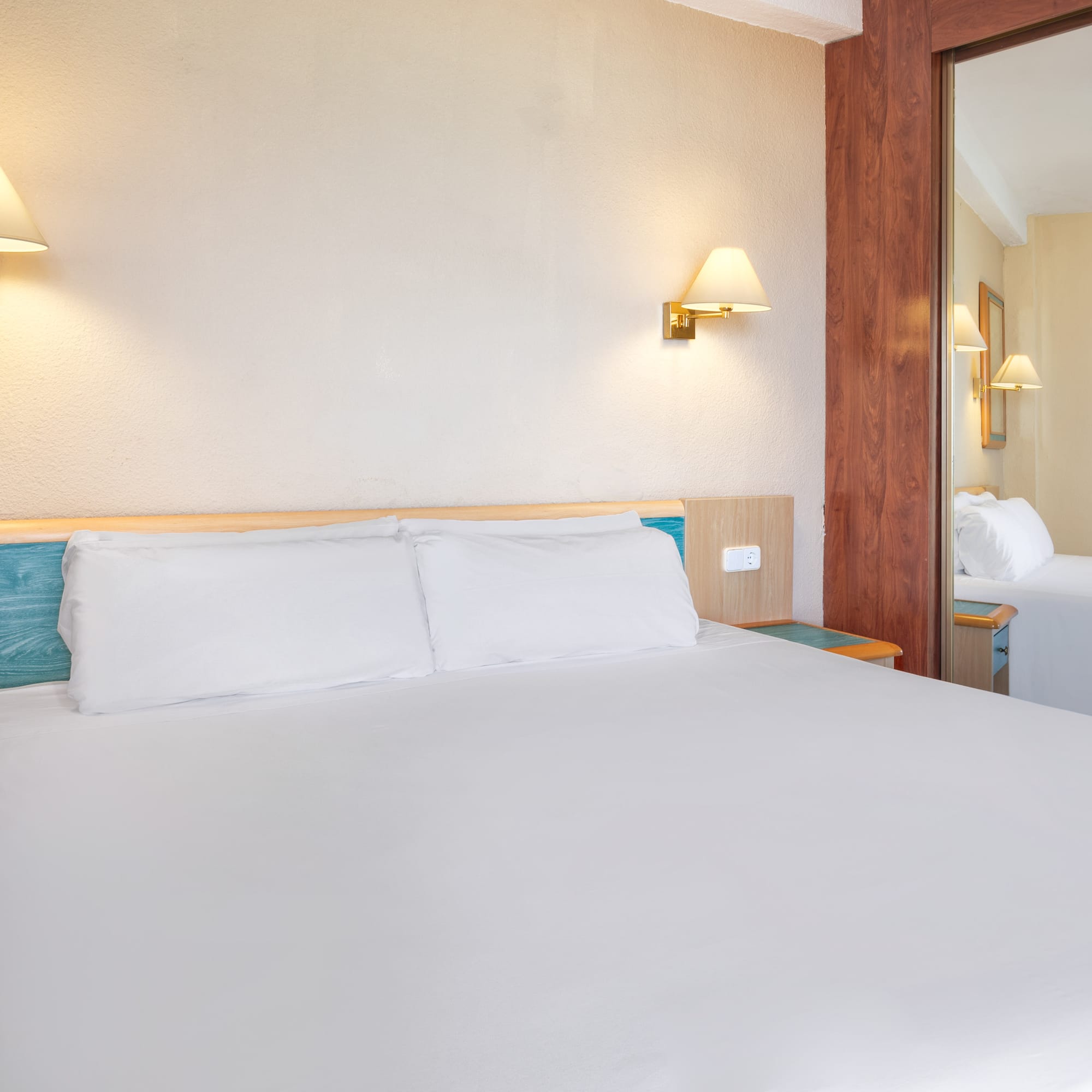 a bed with white sheets and a mirror