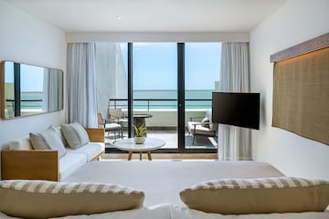 a room with a television and a view of the ocean