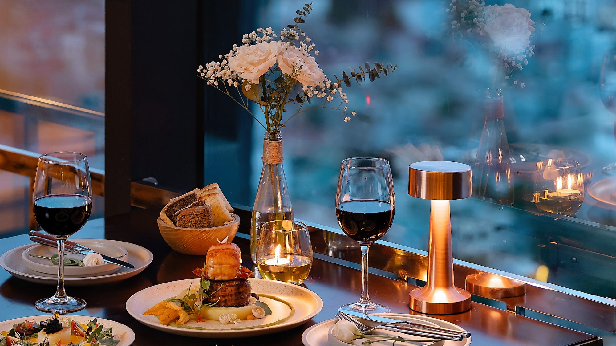 a table with plates of food and wine glasses