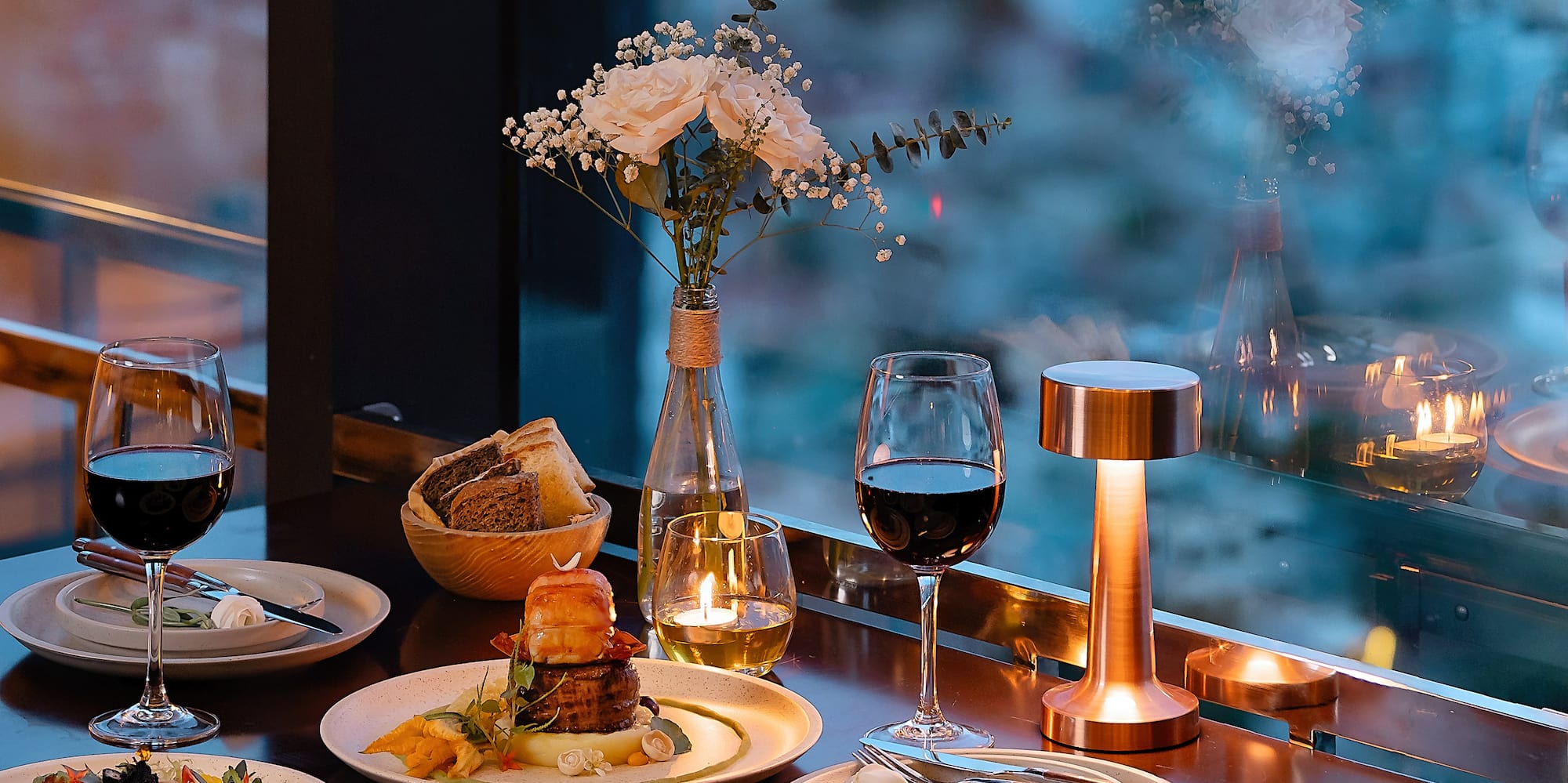 a table with plates of food and wine glasses