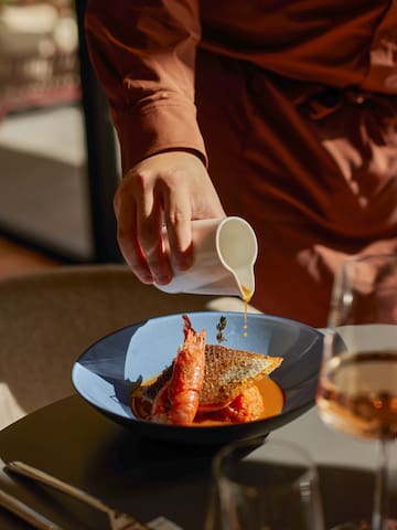 a person pouring sauce on a plate of food